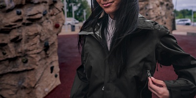 A woman wearing a jacket with rock climbing walls behind her.