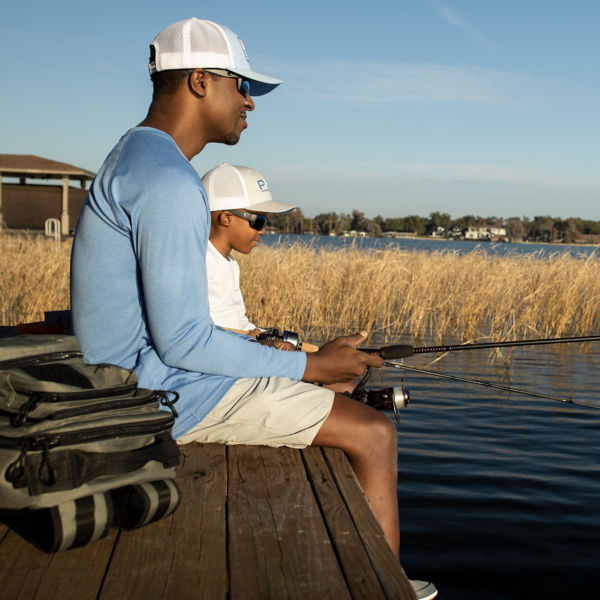 A father and son sit on a dock and fish