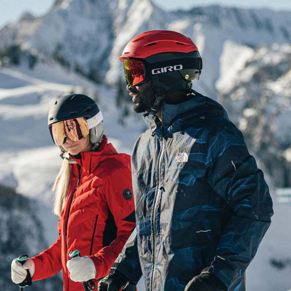 two skiers on a mountain wearing helmets