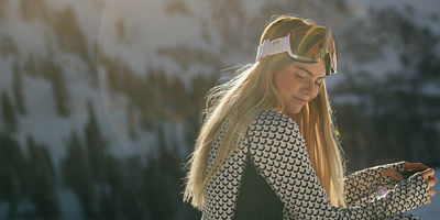Female Snowboarder on a mountain wearing baselayer and goggles