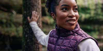 Camper in the woods wearing a vest and baselayer