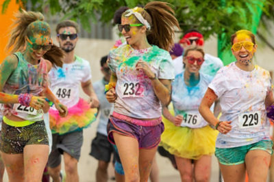 women and one man running in a color fun run 