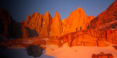 Two climbers approaching Mount Whitney, the tallest peak in the continental United States, at sunrise.