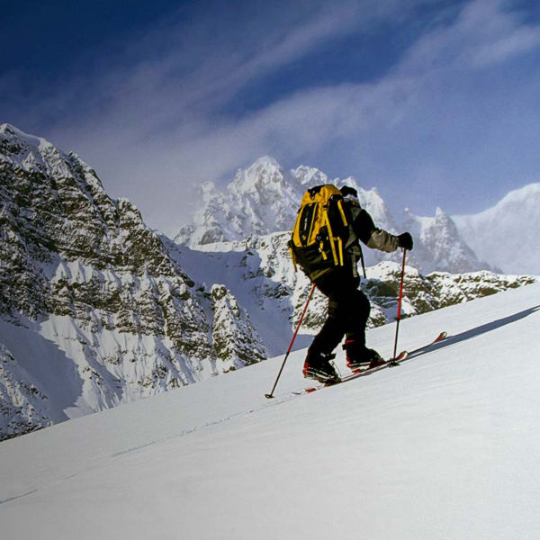 A man backcountry ski touring up a mountain