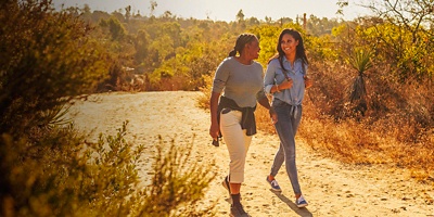 Mother And Adult Daughter Hiking Outdoors In Countryside