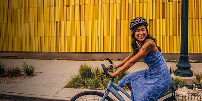 A woman smiles and rides a bike