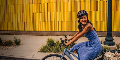 A woman smiles and rides a bike