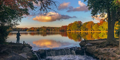 A man fishing next to a waterfall on Long Island, New York
