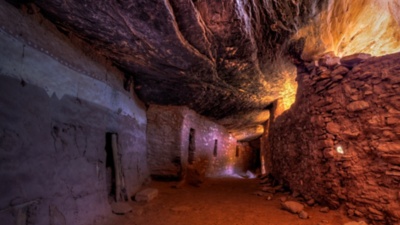 Indirect bounce light creates colors in an ancient interior hallway below a sloping layered cliff wall in the late 13th century Moon House in McCloyd Canyon, Bears Ears National Monument.