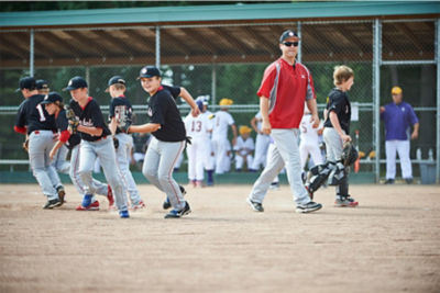 Image of coach and players on the baseball field