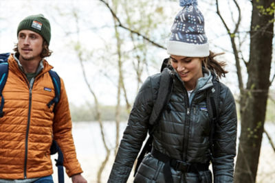 man and woman hiking throught he woods wearing cold weather clothes and backpacks