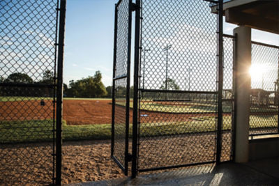 looking at a baseball field through a dugout cage 