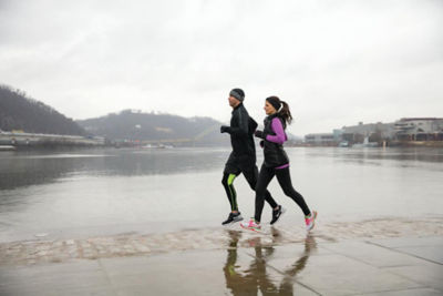 Picture of two people out for a jog in a wet pier with a gray sky.