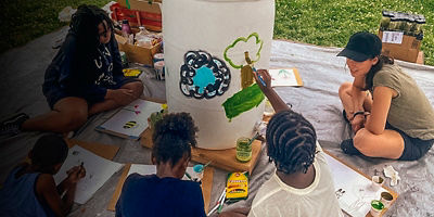 Children paint a rain barrel at an event