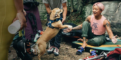 Climber sitting on a crash pad with a dog
