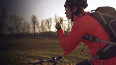 Woman eats protein bar ride on mountain bike in nature. 