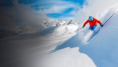 Skier skiing downhill in high mountains in fresh powder snow.