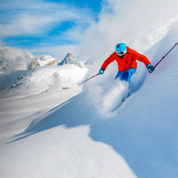 Skier skiing downhill in high mountains in fresh powder snow.