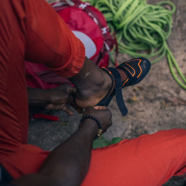 A man gets ready to climb by putting on climbing shoes