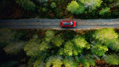 Aerial view of red car for traveling with a roof rack on a country road