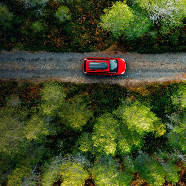 Aerial view of red car for traveling with a roof rack on a country road