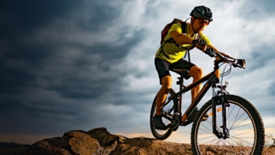 Cyclist Riding the Mountain Bike on Rocky Trail at Sunset.