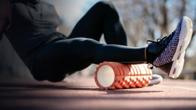 Athlete stretches using foam roller.