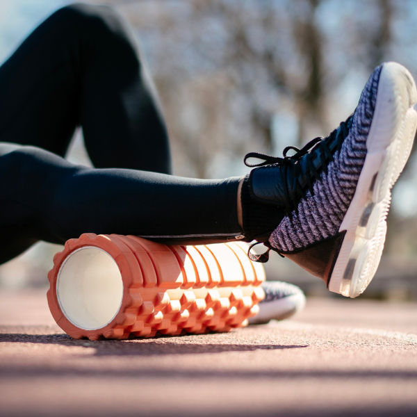 Athlete stretches using foam roller.