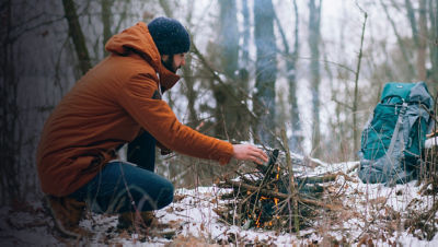 A man making camp fire in the winter woods