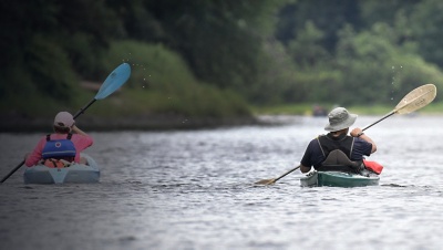 Two kayakers paddle in sync along the Delaware River.