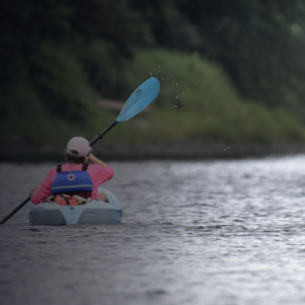 Two kayakers paddle in sync along the Delaware River.