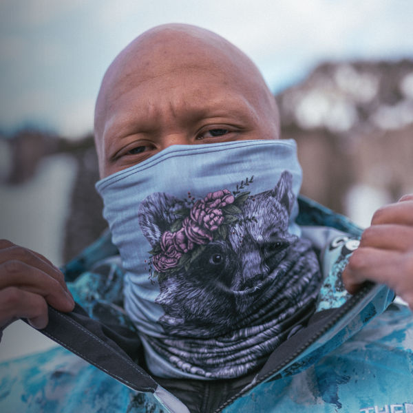 A snowboarder puts on a face mask