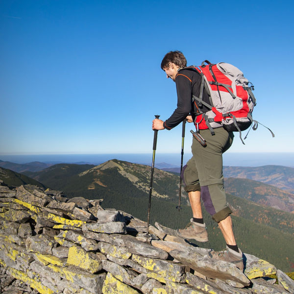 A woman walking on the rocky ridge of the mountain with beautiful high altitude landscape view on the background