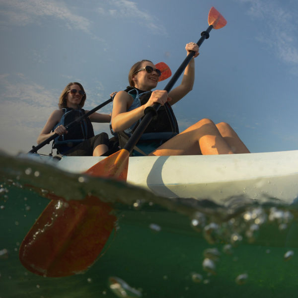 Two young women paddling blue kayak