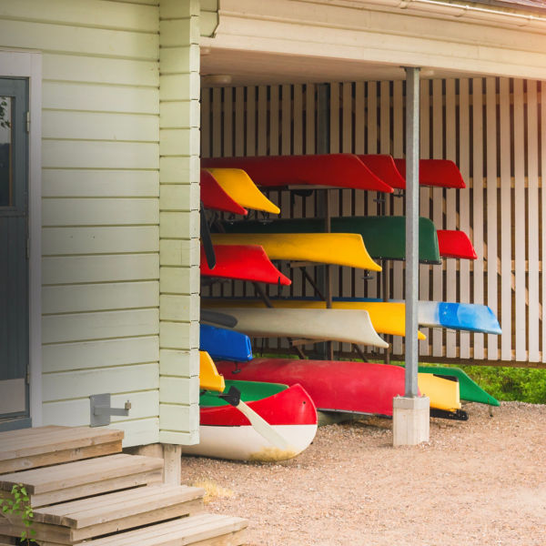 Collection of vibrant colorful plastic recreational canoe and kayaks stored storage rack