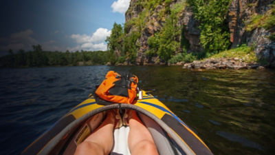 View of a rock face from the perspective of a kayaker in an orange kayak.