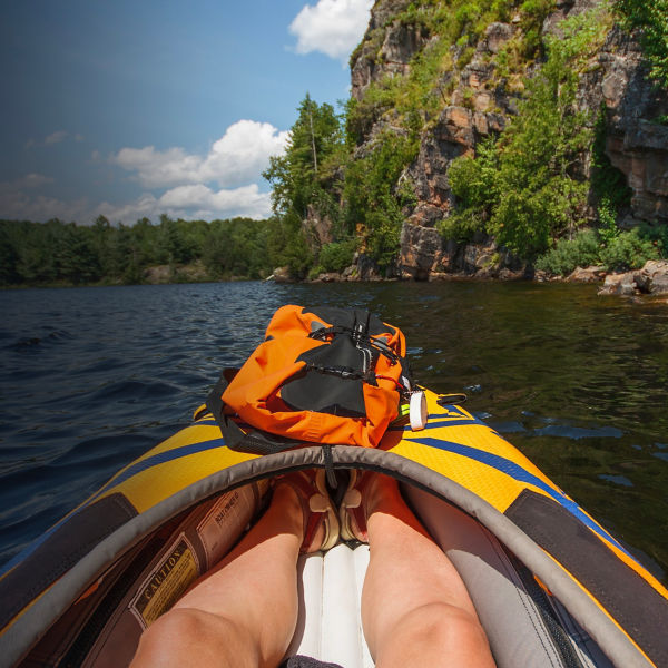 View of a rock face from the perspective of a kayaker in an orange kayak.