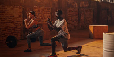 A woman and a man doing leg lunge exercise workout at gym