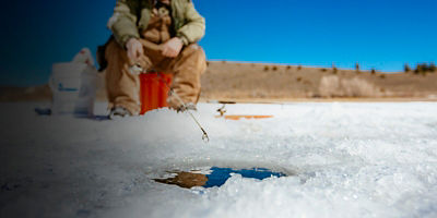 A man is fishing for trout on iced over Panguitch Lake, Dixie National Forest