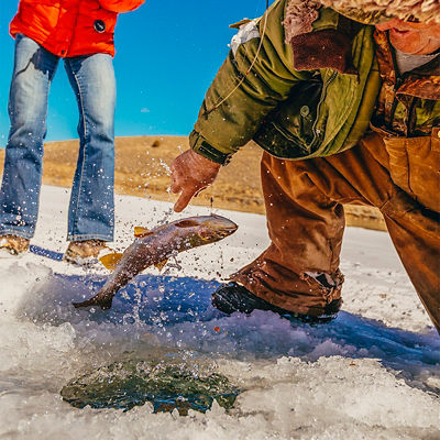 A man is teaching a woman to fish for trout on iced over Panguitch Lake, Dixie National Forest, Utah, USA