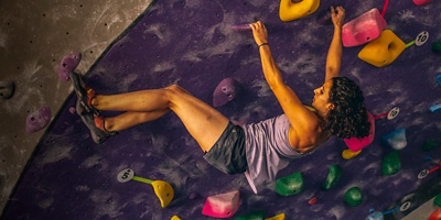 A woman climbs a rock wall at ASCEND Climbing gym