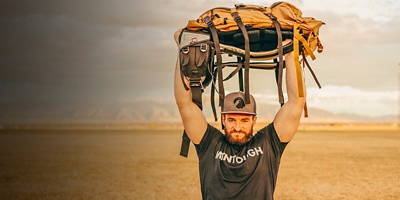 A man uses a backpack to do a Pack Sit-up Military Press