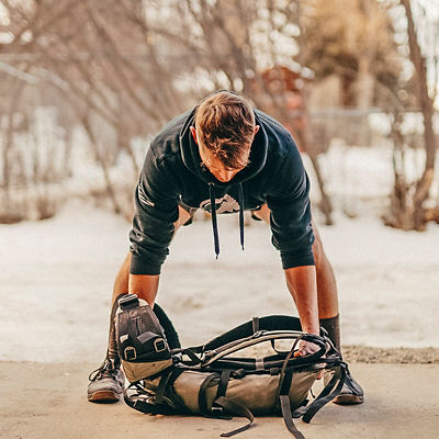 A man uses a backpack to do a Heavy Pack Bent-over Row