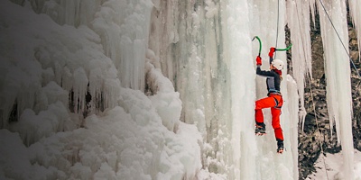 A woman Ice climbs a waterfall.