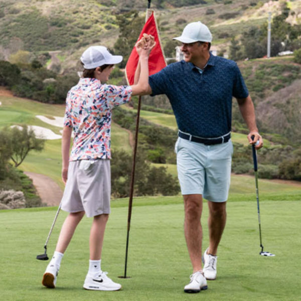 older and younger man high fiving on course