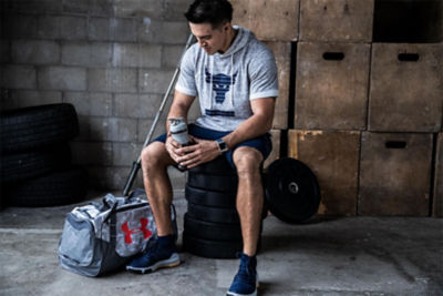 Man sitting in a gym with a water bottle and gym bag