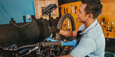 A man assembles a saddle on a bicycle frame in a workshop