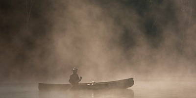 A person in a canoe in the fog