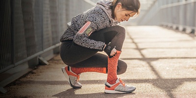 Pretty Caucasian sportswoman preparing for running.