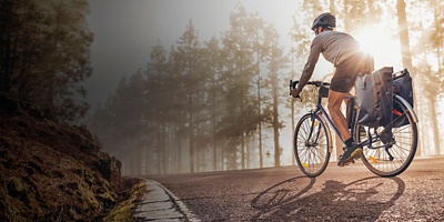 Cyclist on a bicycle with panniers riding along a foggy forest road